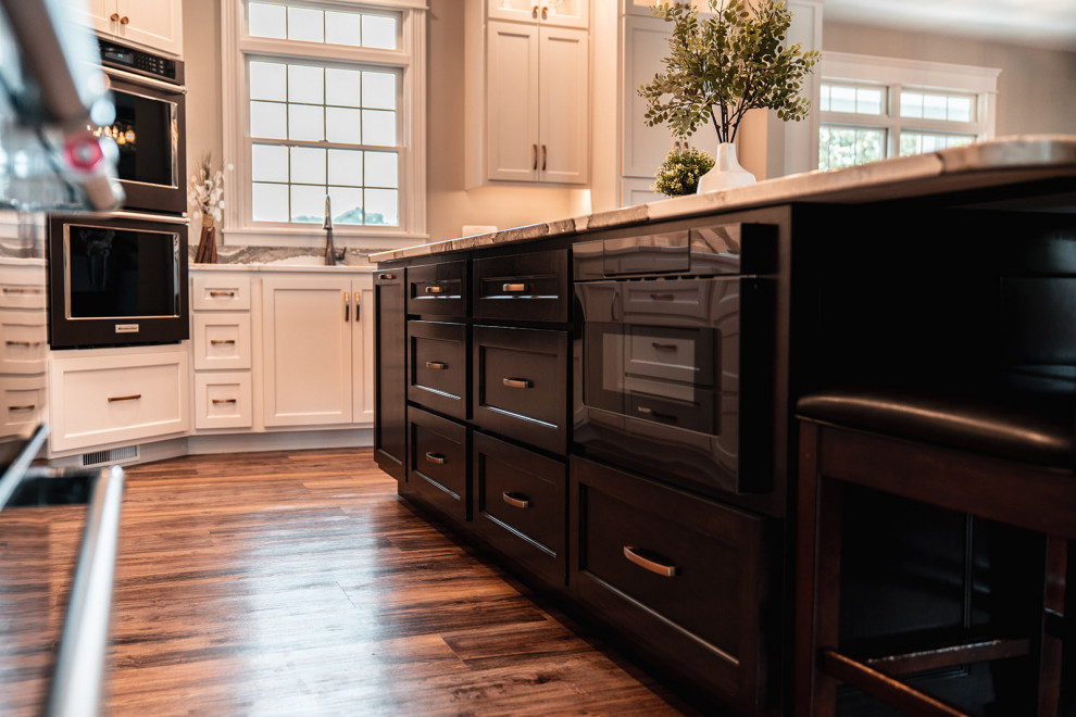 Large transitional l-shaped medium tone wood floor and brown floor open concept kitchen photo with an undermount sink, flat-panel cabinets, white cabinets, quartz countertops, multicolored backsplash, quartz backsplash, black appliances, an island and multicolored countertops