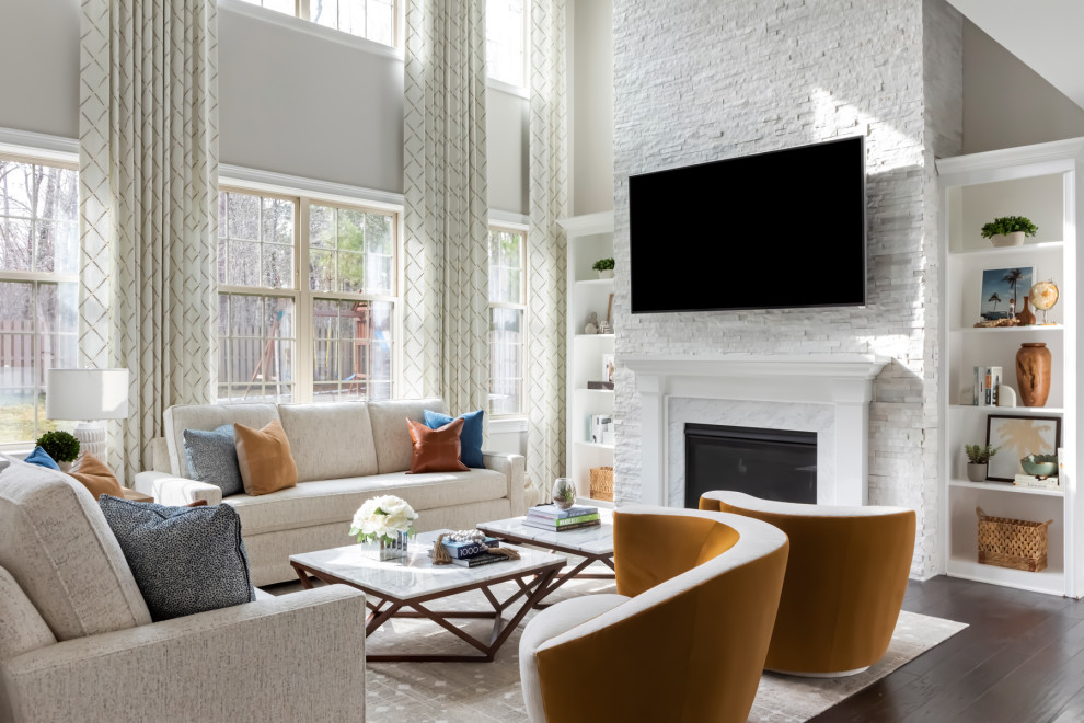 Modelo de salón abierto minimalista de tamaño medio con paredes grises, suelo de madera en tonos medios, todas las chimeneas, marco de chimenea de piedra, televisor colgado en la pared y suelo marrón