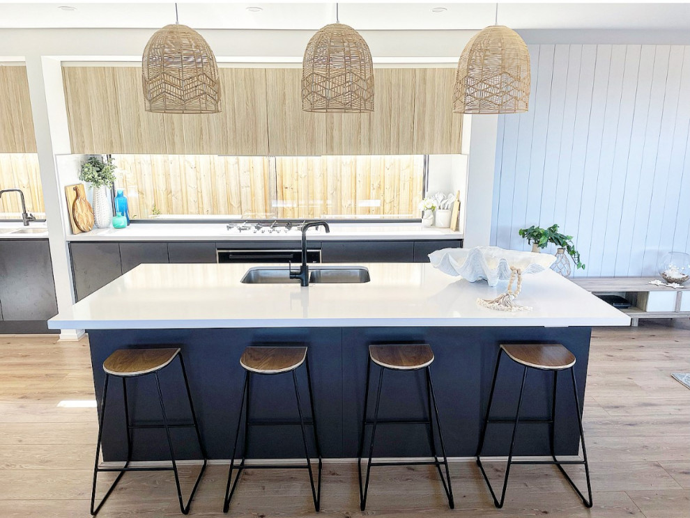 Photo of a large beach style galley open plan kitchen in Geelong with an undermount sink, light wood cabinets, quartz benchtops, window splashback, stainless steel appliances, vinyl floors, with island and white benchtop.