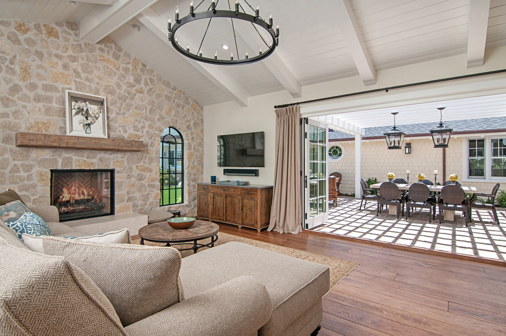 Inspiration for a large traditional open concept family room in San Diego with a game room, beige walls, medium hardwood floors, a standard fireplace, a stone fireplace surround and a wall-mounted tv.
