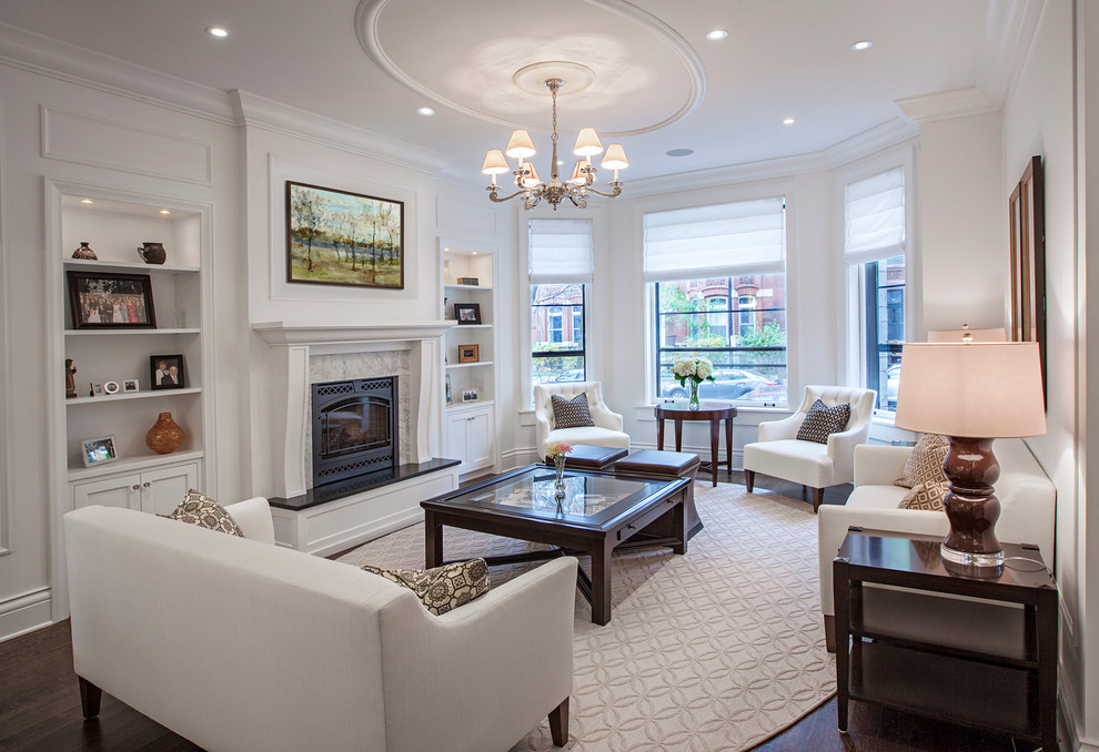 This is an example of a large traditional formal enclosed living room in Chicago with white walls, dark hardwood floors, a standard fireplace, a wood fireplace surround and no tv.