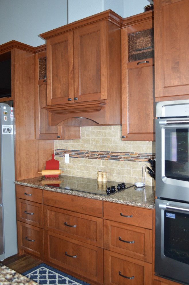 Mid-sized transitional l-shaped kitchen photo with a farmhouse sink, shaker cabinets, medium tone wood cabinets, quartzite countertops, beige backsplash, stainless steel appliances and an island