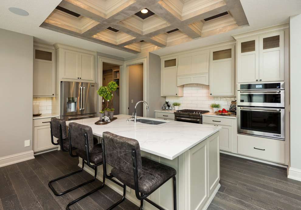 This is an example of a mid-sized transitional l-shaped open plan kitchen in Other with a double-bowl sink, shaker cabinets, white cabinets, marble benchtops, white splashback, stainless steel appliances, porcelain floors, with island, brown floor and white benchtop.