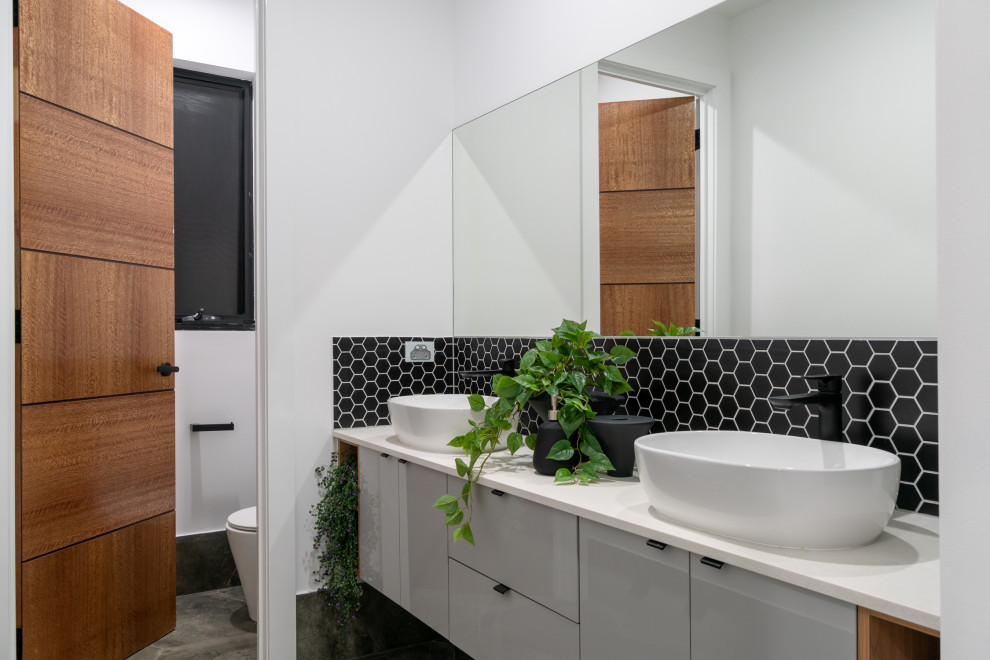 Inspiration for a mid-sized contemporary powder room in Adelaide with grey cabinets, black tile, ceramic tile, mosaic tile floors, quartzite benchtops, grey floor and a freestanding vanity.
