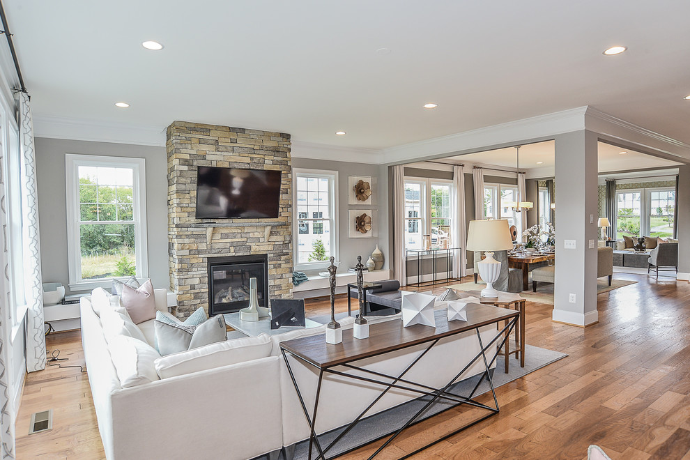 Design ideas for a large transitional open concept family room in DC Metro with grey walls, medium hardwood floors, a standard fireplace, a stone fireplace surround and a wall-mounted tv.