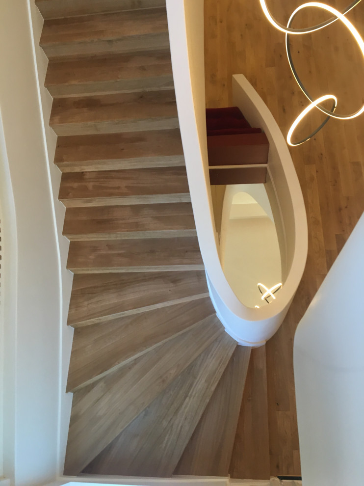 Gewendelte, Große Moderne Holztreppe mit Holz-Setzstufen, Mix-Geländer und vertäfelten Wänden in Paris