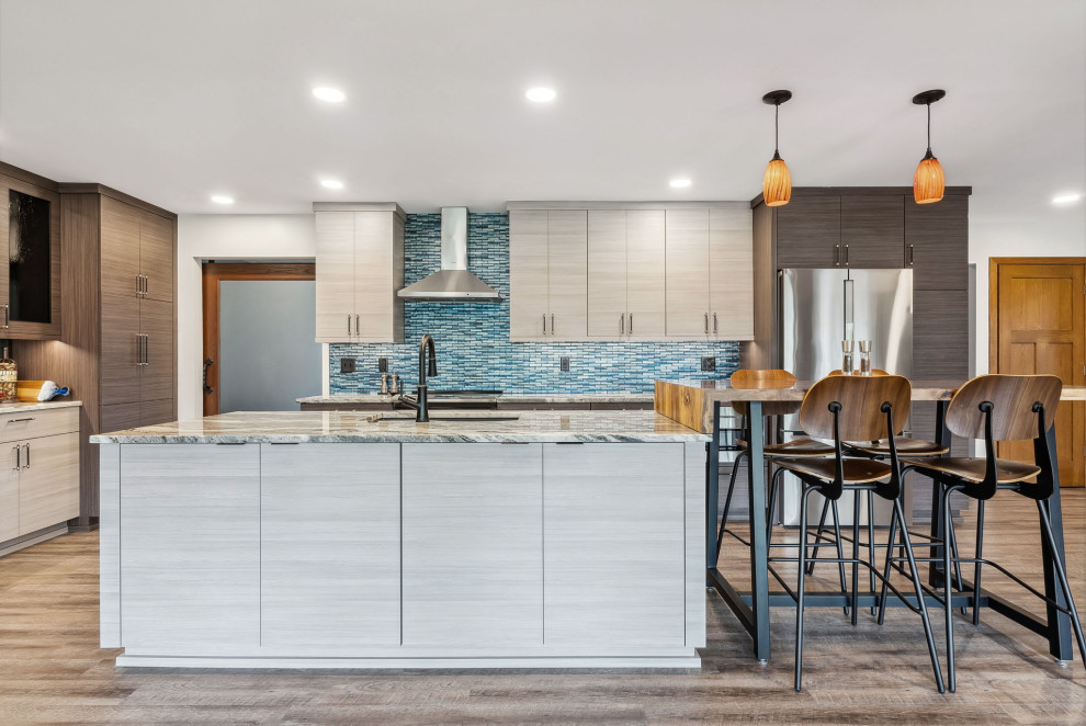 Design ideas for a mid-sized contemporary l-shaped open plan kitchen in Columbus with an undermount sink, flat-panel cabinets, beige cabinets, granite benchtops, blue splashback, glass tile splashback, stainless steel appliances, laminate floors, with island, beige floor and white benchtop.