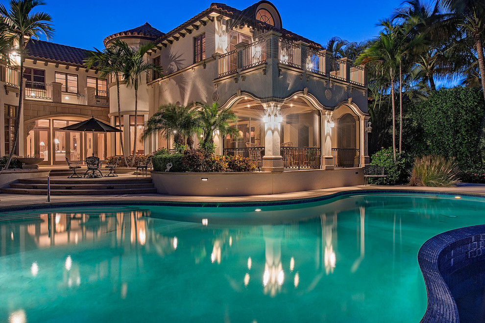 This is an example of a large tropical backyard custom-shaped pool in Miami.