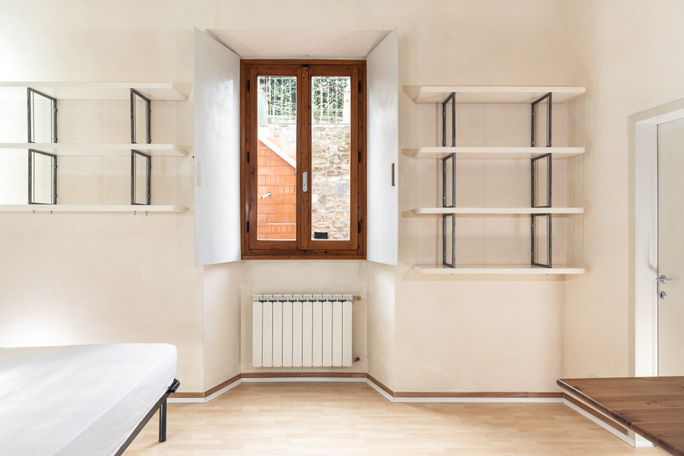 Foto di una piccola camera matrimoniale design con pareti beige, pavimento in laminato e pavimento beige