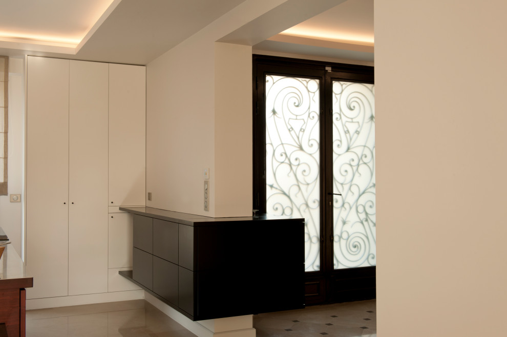 Idee per un ingresso minimal di medie dimensioni con pareti beige, pavimento in marmo, una porta a due ante, una porta nera, pavimento beige e soffitto ribassato