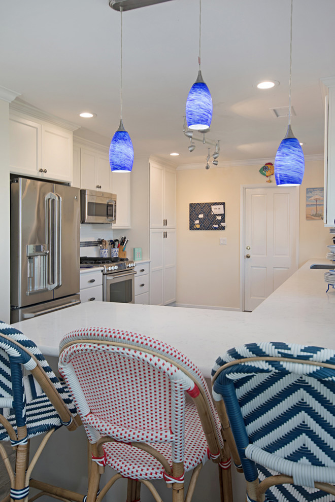 This is an example of a large beach style u-shaped eat-in kitchen in San Diego with a drop-in sink, recessed-panel cabinets, white cabinets, granite benchtops, white splashback, subway tile splashback, stainless steel appliances, medium hardwood floors, a peninsula and brown floor.