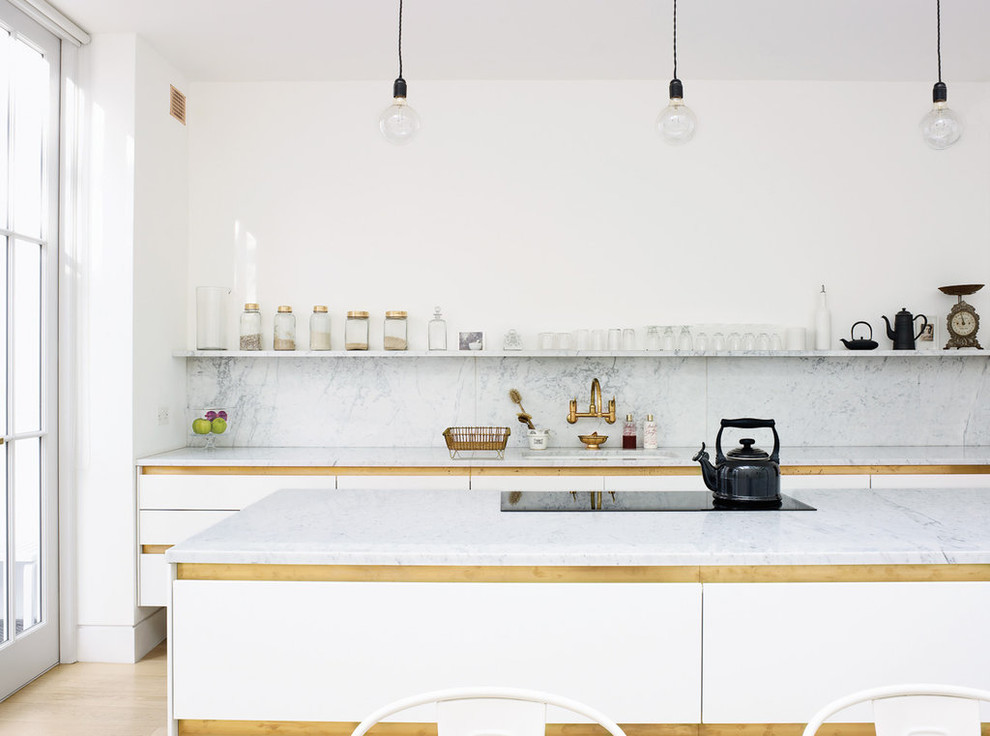 Design ideas for a scandinavian single-wall eat-in kitchen in London with flat-panel cabinets, white cabinets, marble benchtops, white splashback, stone slab splashback, light hardwood floors and with island.