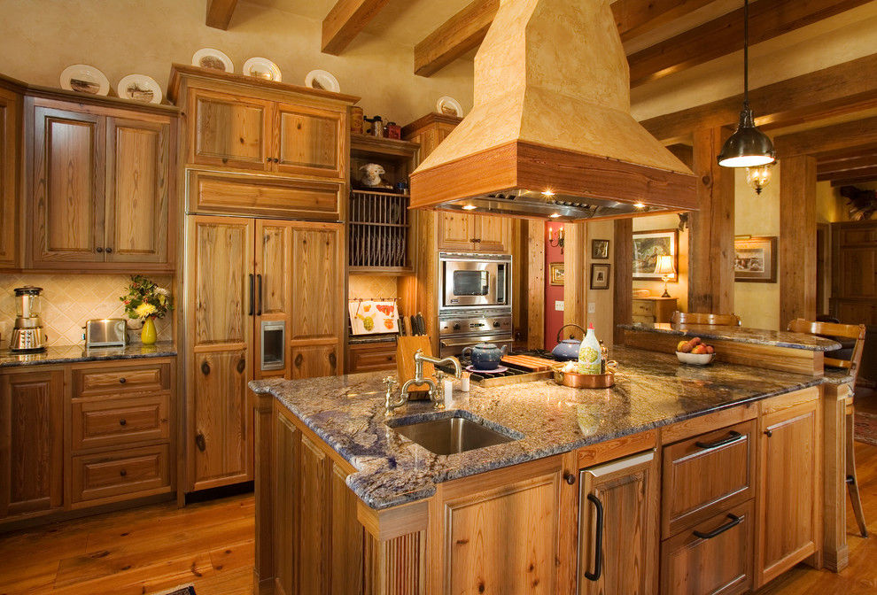 Inspiration for a rustic medium tone wood floor kitchen remodel in Atlanta with an undermount sink, raised-panel cabinets, medium tone wood cabinets, beige backsplash, paneled appliances and an island