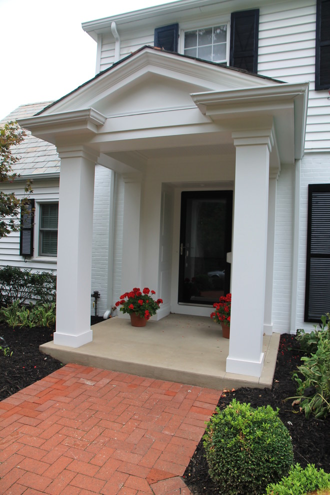 This is an example of a mid-sized traditional concrete front porch design in Columbus with a roof extension.