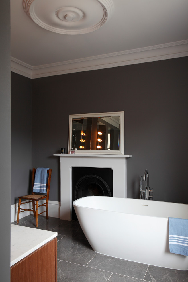 This is an example of a large traditional master bathroom in London with flat-panel cabinets, dark wood cabinets, a freestanding tub, an alcove shower, a wall-mount toilet, gray tile, stone slab, grey walls, limestone floors, a console sink, quartzite benchtops, grey floor, a hinged shower door, white benchtops, an enclosed toilet, a double vanity, a built-in vanity and coffered.