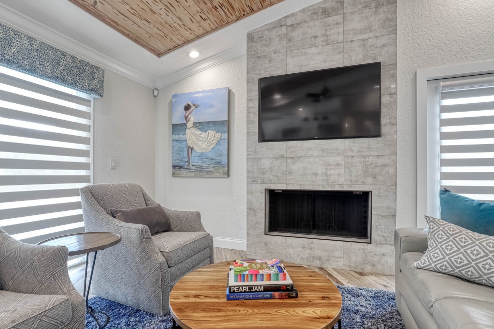Photo of a mid-sized contemporary open concept family room in Miami with white walls, light hardwood floors, a ribbon fireplace, a stone fireplace surround, a wall-mounted tv, beige floor and vaulted.