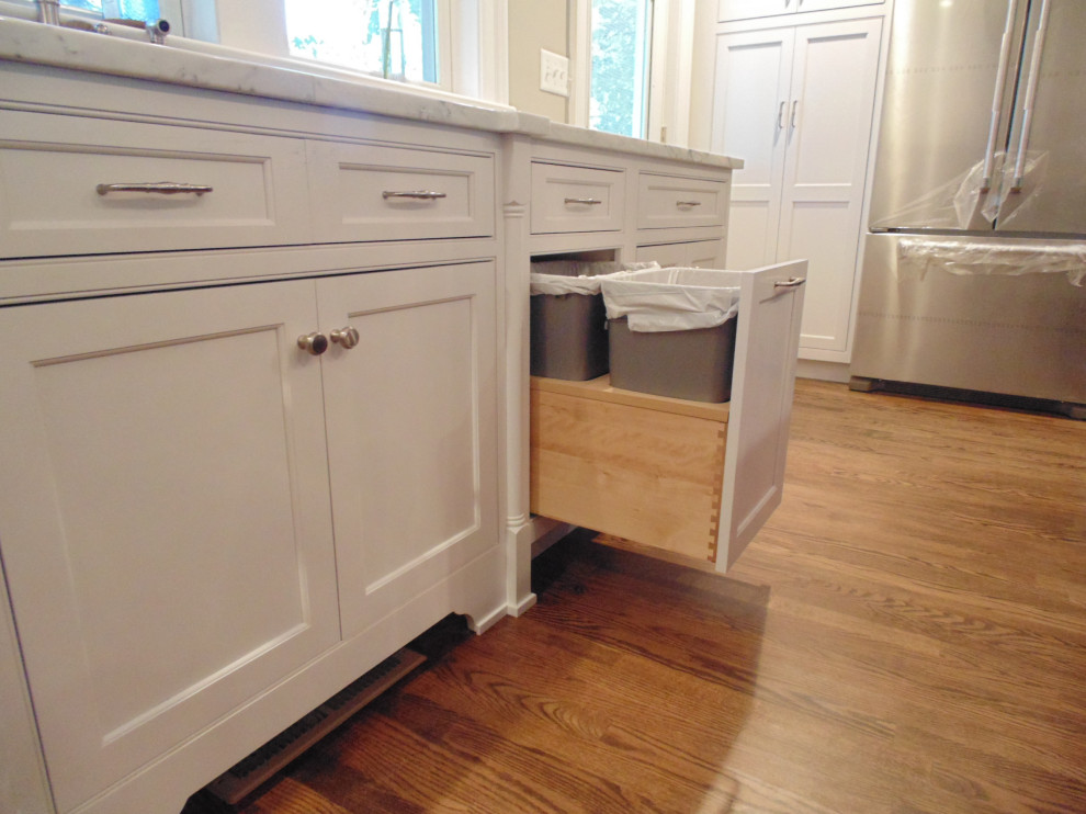 Large transitional u-shaped medium tone wood floor and brown floor eat-in kitchen photo with an undermount sink, flat-panel cabinets, white cabinets, marble countertops, white backsplash, subway tile backsplash, stainless steel appliances, an island and white countertops