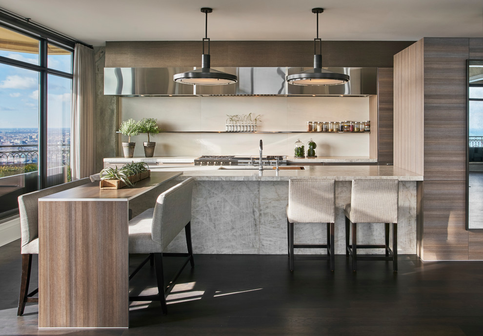 Photo of a mid-sized contemporary galley eat-in kitchen with an undermount sink, marble benchtops, white splashback, stone slab splashback, stainless steel appliances, dark hardwood floors, with island, brown floor, flat-panel cabinets and brown cabinets.