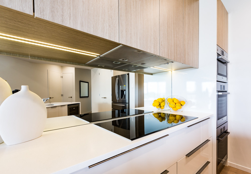 Photo of a contemporary kitchen in Auckland with mirror splashback.
