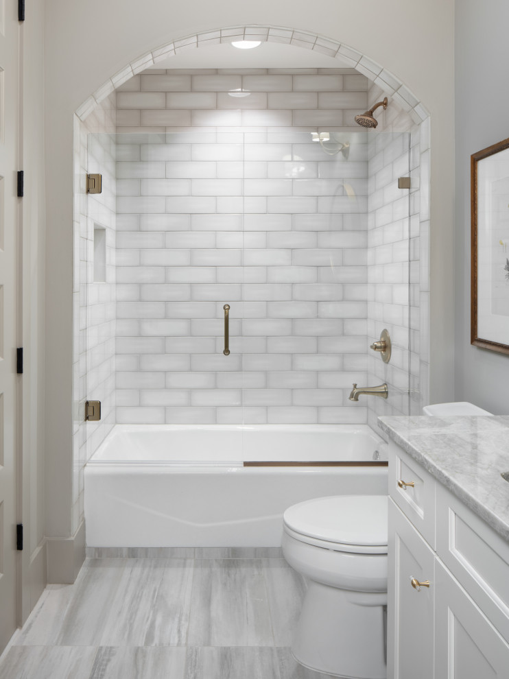 Photo of a mid-sized traditional bathroom in Birmingham with raised-panel cabinets, white cabinets, an alcove tub, a shower/bathtub combo, a two-piece toilet, gray tile, ceramic tile, beige walls, ceramic floors, an undermount sink, engineered quartz benchtops, grey floor, a hinged shower door, beige benchtops, a single vanity and a built-in vanity.