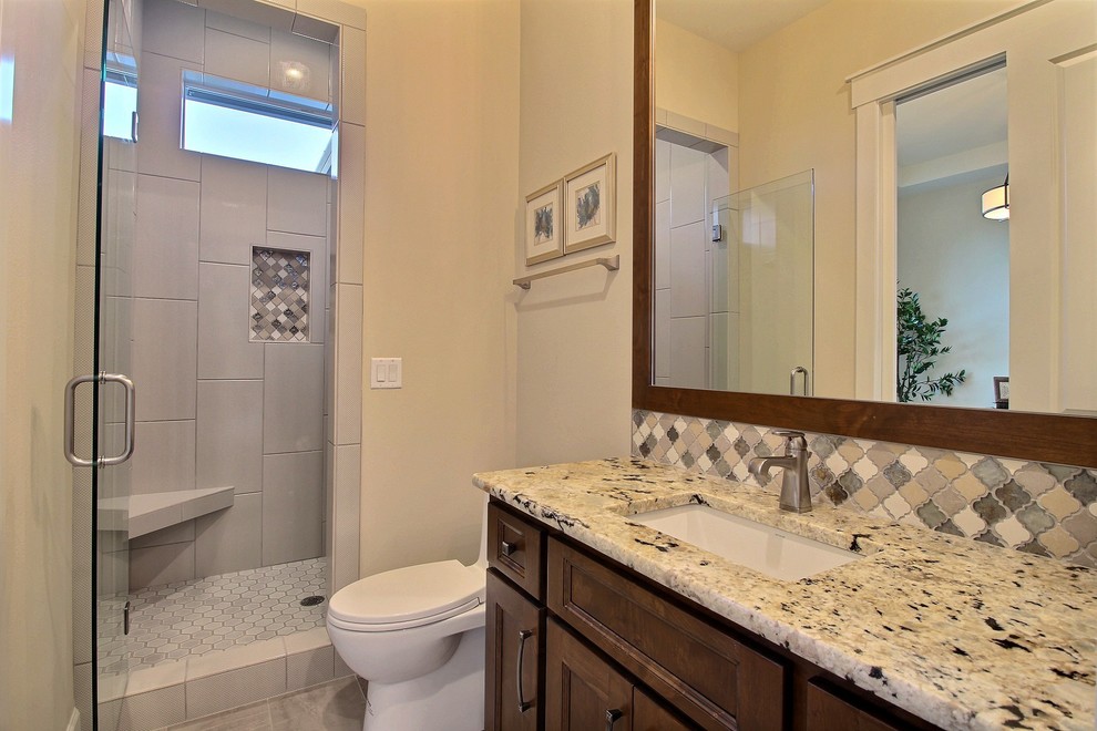 Inspiration for a mid-sized transitional 3/4 wet room bathroom in Portland with recessed-panel cabinets, medium wood cabinets, a two-piece toilet, gray tile, ceramic tile, beige walls, ceramic floors, an undermount sink, granite benchtops, beige floor and a hinged shower door.