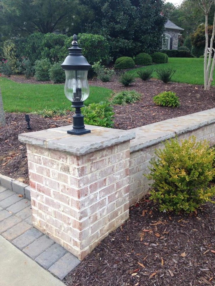 Inspiration for a mid-sized traditional front yard full sun garden in Other with a retaining wall and brick pavers.