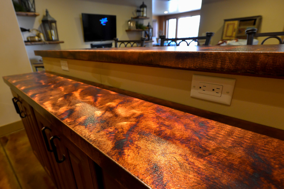 Inspiration for a mid-sized country galley seated home bar in Denver with a drop-in sink, raised-panel cabinets, dark wood cabinets, copper benchtops, multi-coloured splashback, stone tile splashback, concrete floors and brown floor.