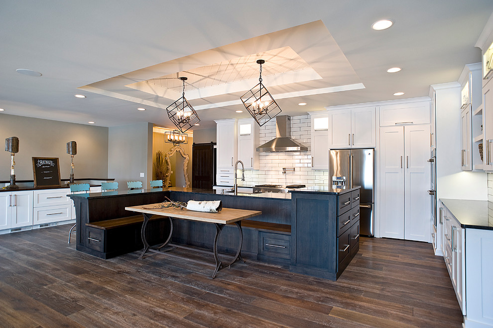 Eat-in kitchen - large transitional l-shaped dark wood floor and brown floor eat-in kitchen idea with an undermount sink, white cabinets, granite countertops, white backsplash, subway tile backsplash, stainless steel appliances, an island and shaker cabinets