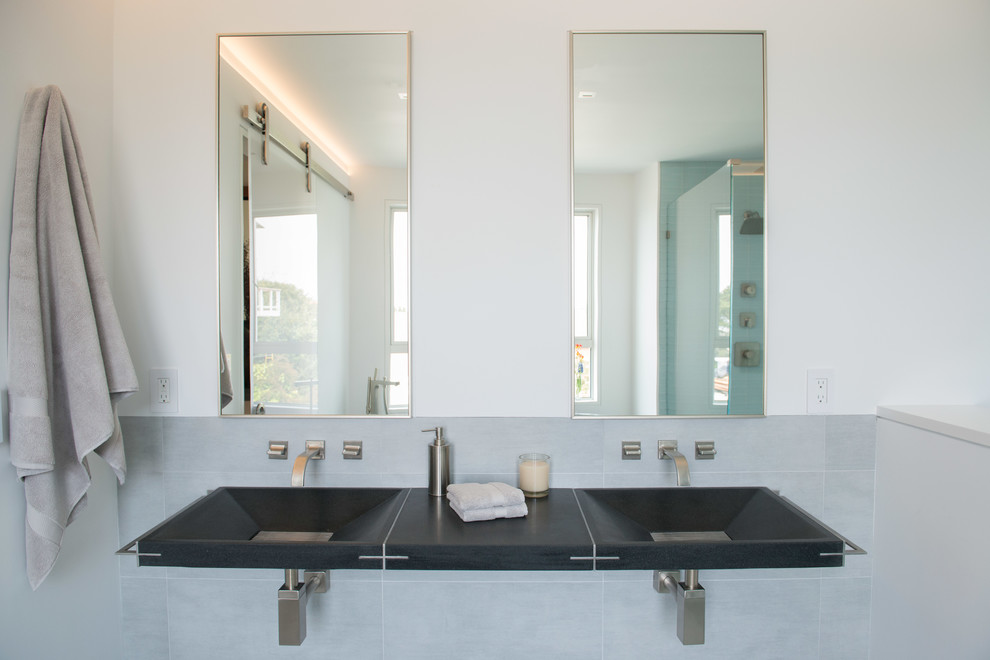 Inspiration for a mid-sized modern master bathroom in San Francisco with an integrated sink, flat-panel cabinets, black cabinets, granite benchtops, a freestanding tub, a curbless shower, a wall-mount toilet, gray tile, glass tile, white walls and porcelain floors.