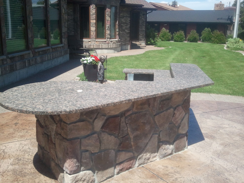 This is an example of a large modern backyard patio in Other with an outdoor kitchen, stamped concrete and no cover.