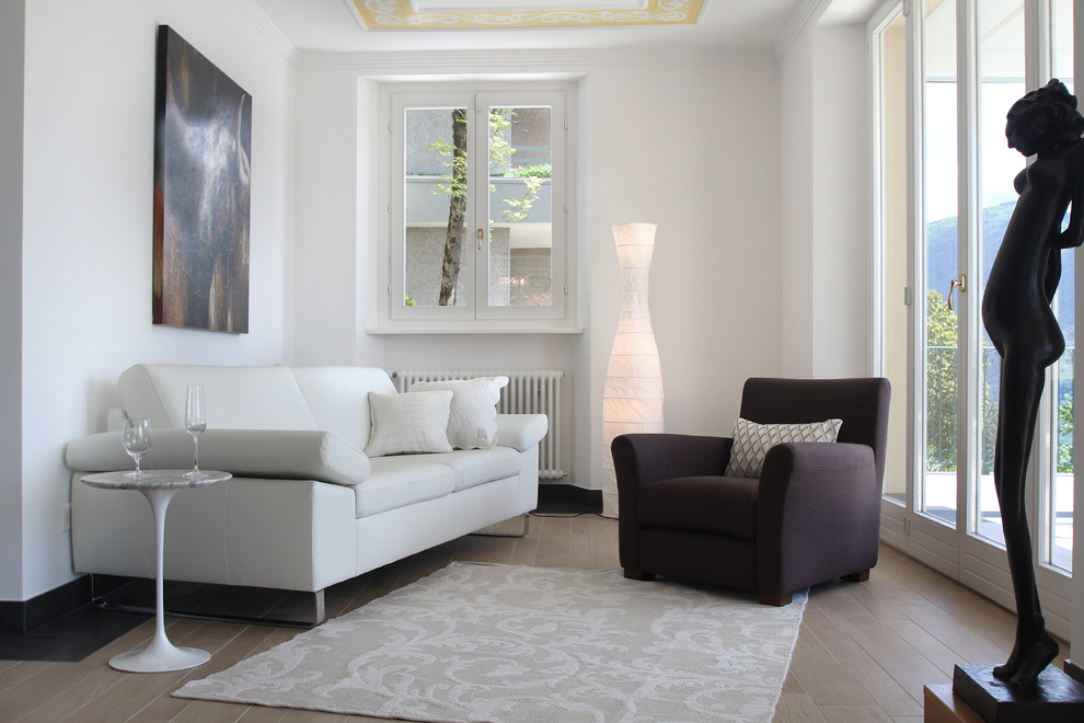 Small contemporary living room in Milan with light hardwood floors and white walls.