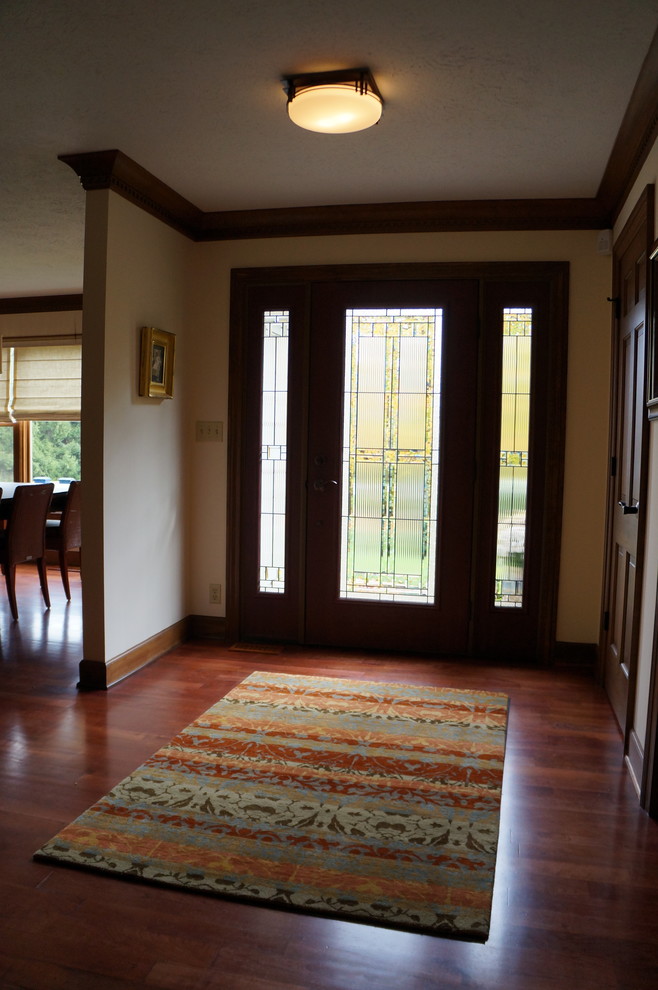 Photo of a mid-sized arts and crafts foyer in Indianapolis with beige walls, medium hardwood floors, a glass front door and a single front door.
