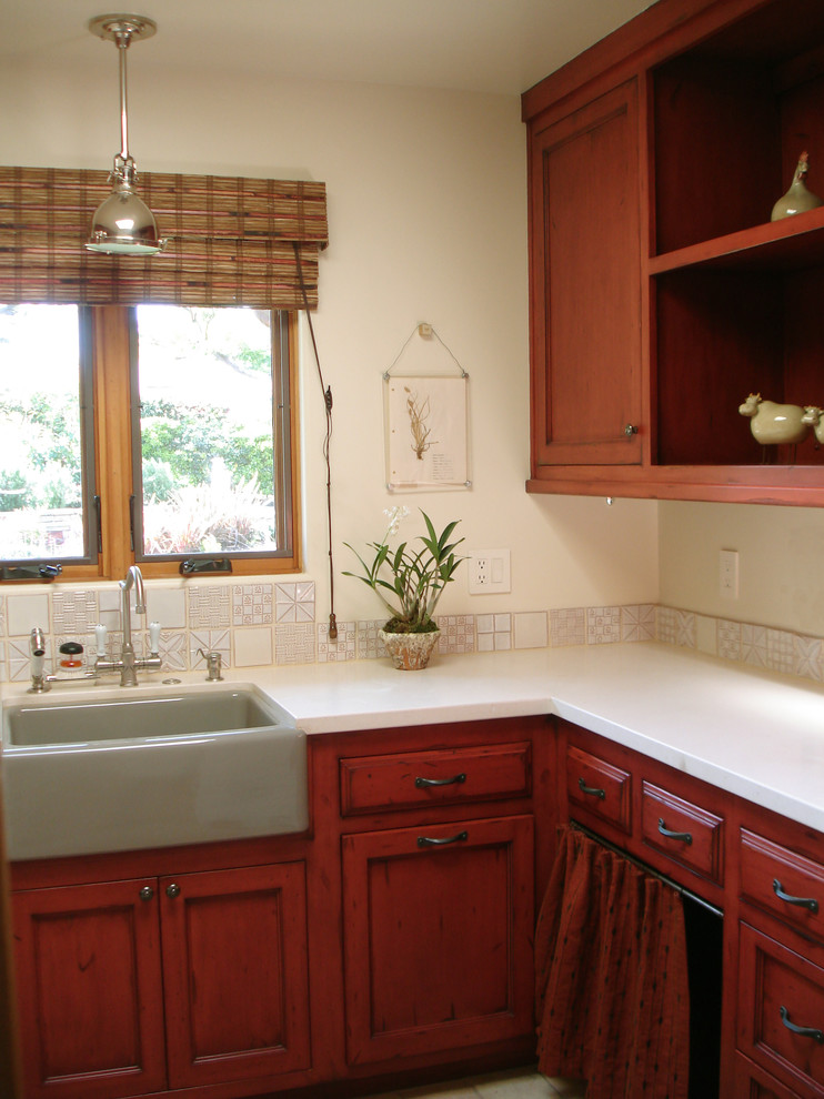 Photo of a traditional laundry room in Los Angeles with a farmhouse sink, recessed-panel cabinets, red cabinets, white walls and terra-cotta floors.