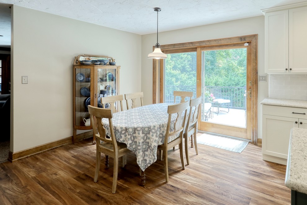 Inspiration for a transitional vinyl floor and brown floor kitchen remodel with an undermount sink, white cabinets, quartz countertops, white backsplash, subway tile backsplash, stainless steel appliances, an island and beige countertops
