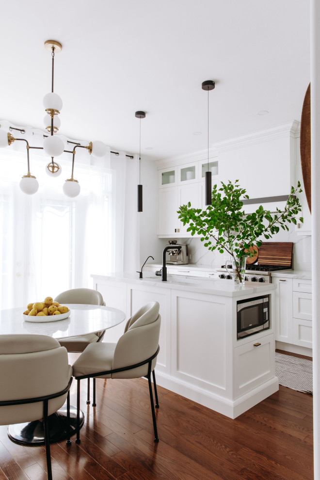 Inspiration for a mid-sized transitional l-shaped dark wood floor and brown floor kitchen remodel in Toronto with shaker cabinets, white cabinets, quartz countertops, white backsplash, quartz backsplash, black appliances, an island, white countertops and an undermount sink