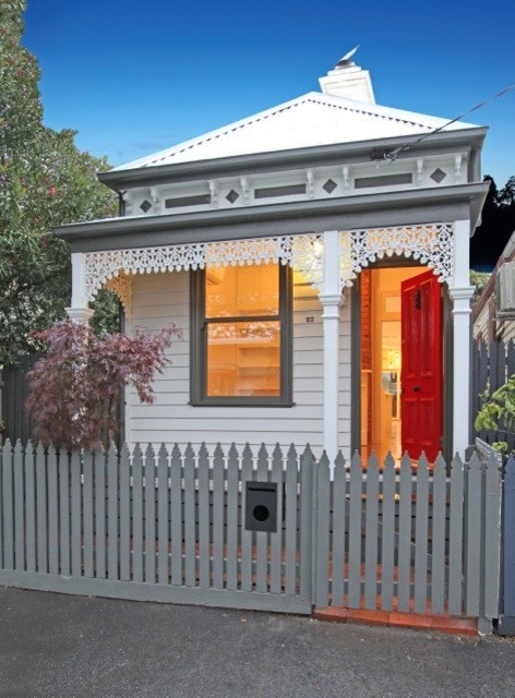 This is an example of a small traditional white house exterior in Melbourne with vinyl siding, a hip roof and a metal roof.
