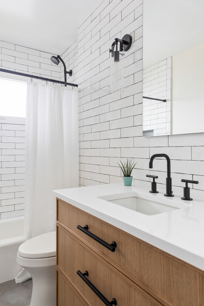 Design ideas for a mid-sized country bathroom in New York with medium wood cabinets, an alcove tub, an alcove shower, a one-piece toilet, white tile, porcelain tile, white walls, an undermount sink, engineered quartz benchtops, grey floor, a shower curtain, white benchtops and a single vanity.