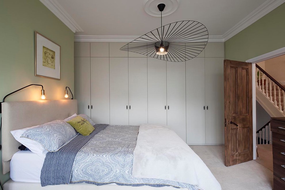 Design ideas for a mid-sized traditional master bedroom in London with green walls, carpet and beige floor.