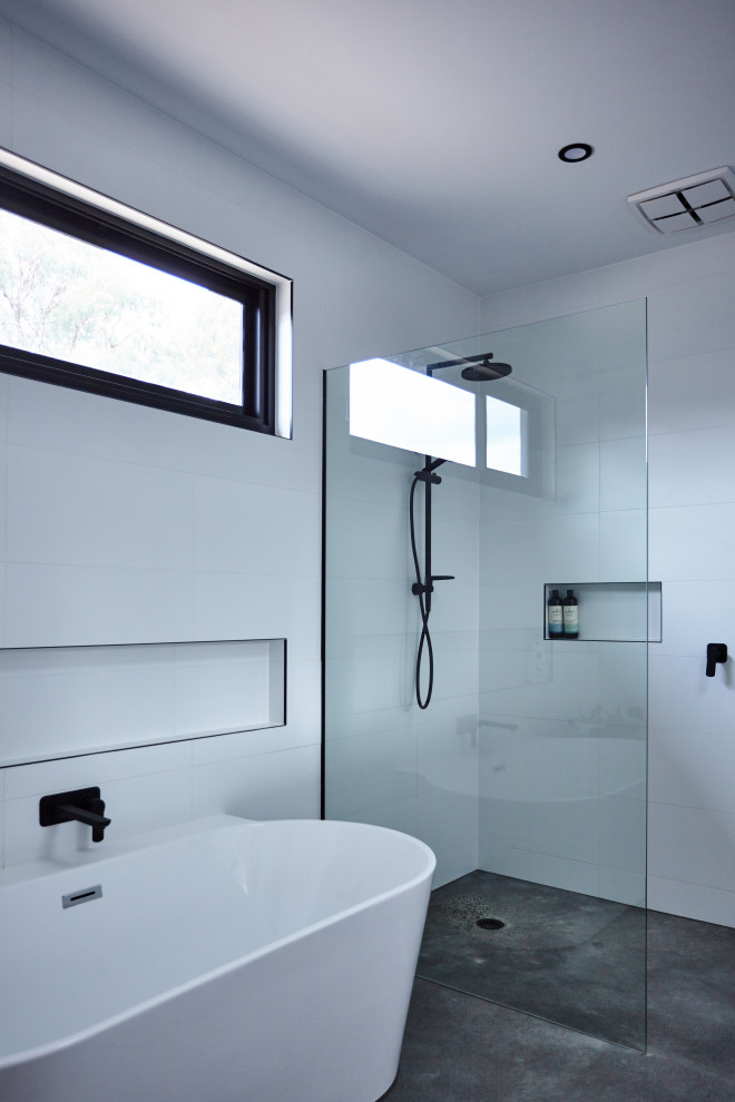 Idéer för att renovera ett mellanstort funkis badrum, med ett fristående badkar, en kantlös dusch, vit kakel, keramikplattor, vita väggar, betonggolv, grått golv och med dusch som är öppen