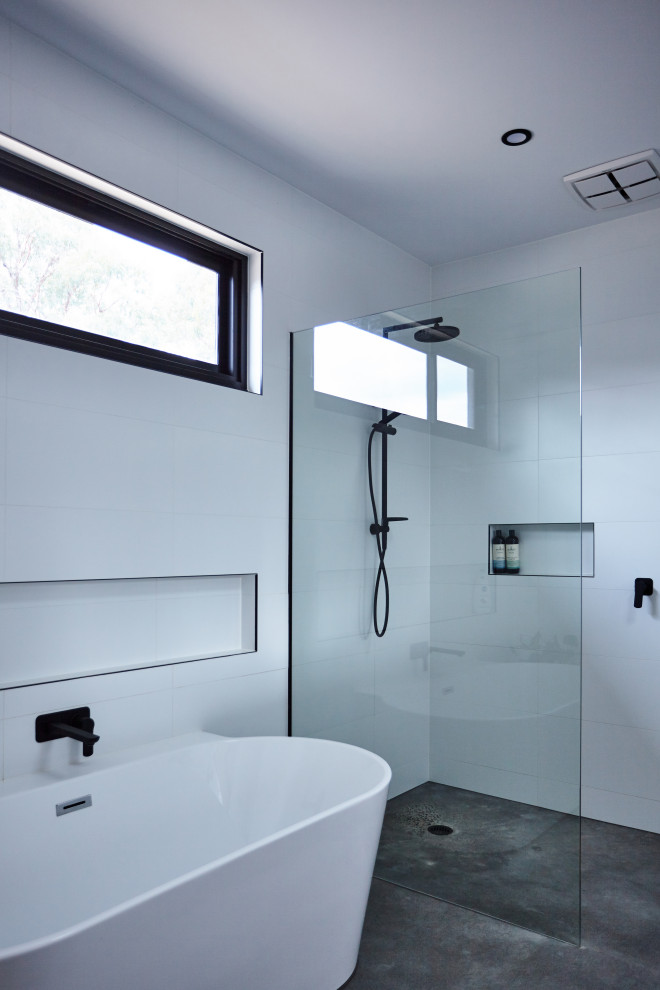 Inspiration for a mid-sized contemporary bathroom in Other with a freestanding tub, a curbless shower, white tile, ceramic tile, white walls, concrete floors, grey floor, an open shower and a single vanity.