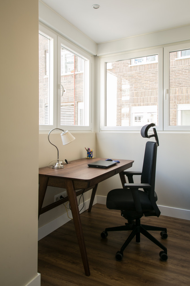 Imagen de despacho contemporáneo pequeño con paredes beige, suelo laminado, suelo marrón y bandeja