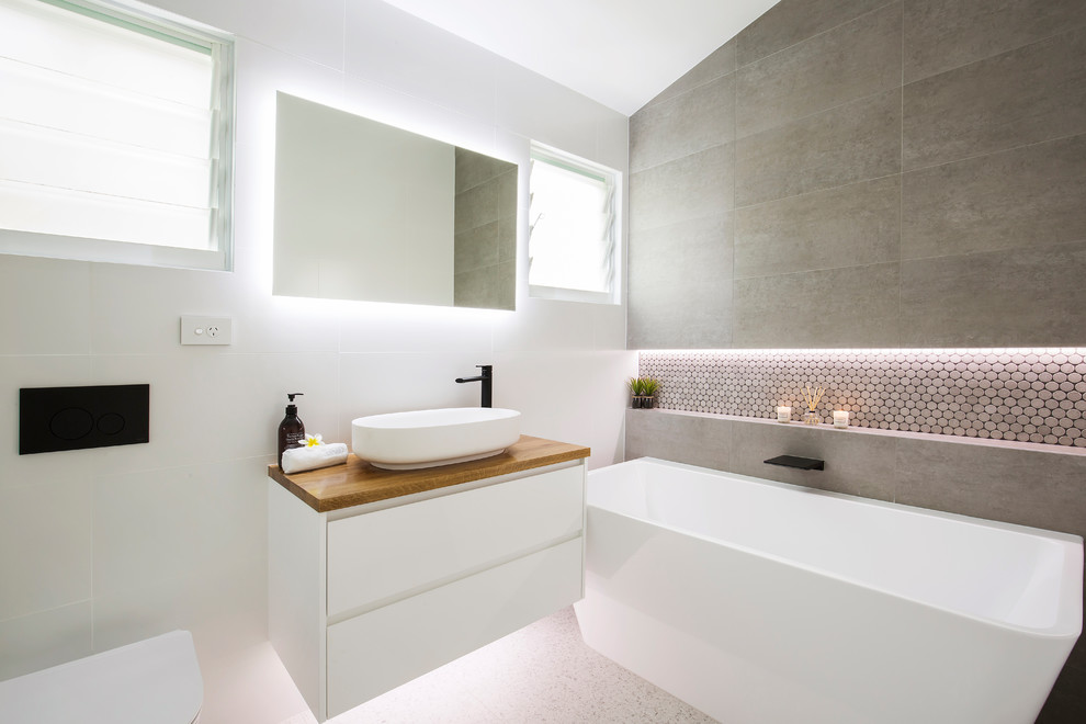 Inspiration for a mid-sized modern master bathroom in Sydney with a freestanding tub, an alcove shower, a wall-mount toilet, black and white tile, ceramic tile, grey walls, ceramic floors, a wall-mount sink, wood benchtops, grey floor and a hinged shower door.