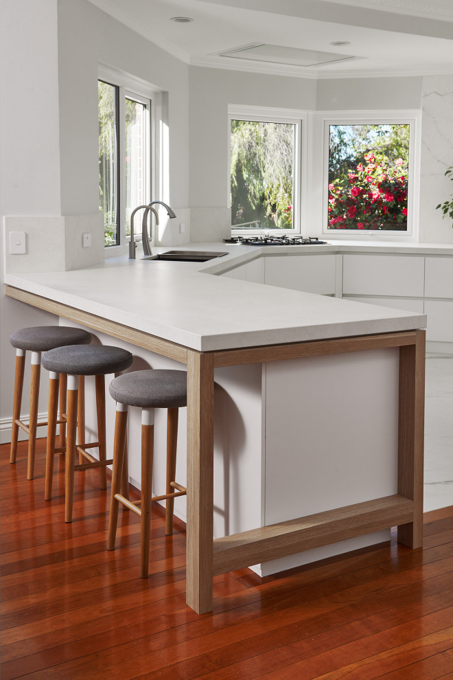 Inspiration for a mid-sized scandinavian u-shaped porcelain tile and white floor eat-in kitchen remodel in Perth with an undermount sink, flat-panel cabinets, white cabinets, quartz countertops, white backsplash, porcelain backsplash, black appliances, an island and white countertops