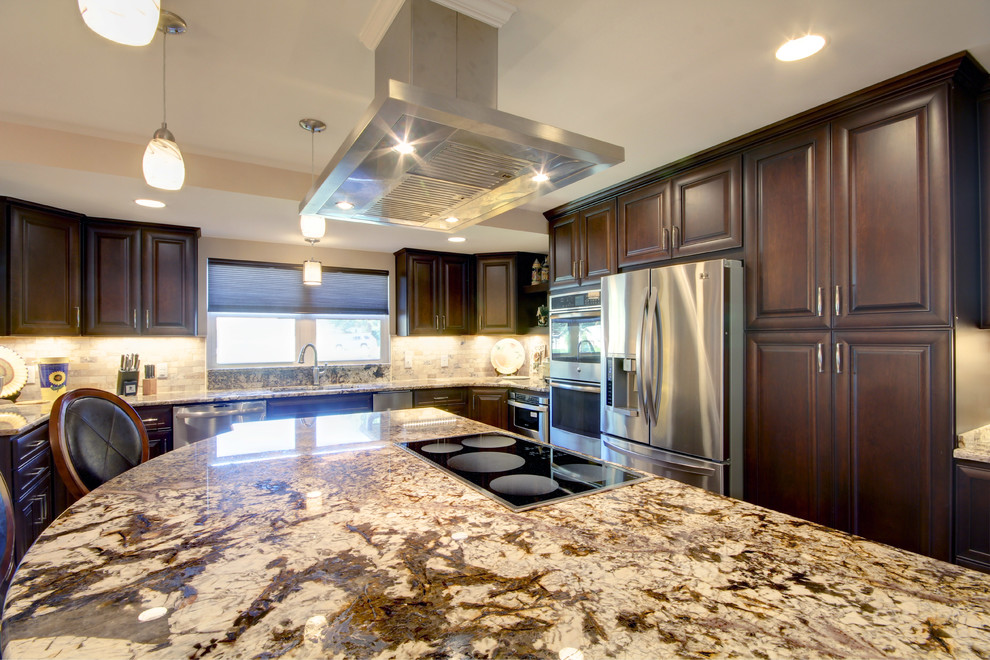 Inspiration for a large transitional l-shaped porcelain tile eat-in kitchen remodel in Miami with an undermount sink, raised-panel cabinets, dark wood cabinets, granite countertops, beige backsplash, stone tile backsplash, stainless steel appliances and an island