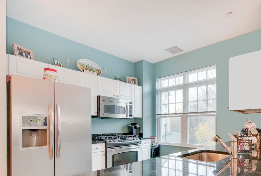 Example of a mid-sized transitional galley ceramic tile enclosed kitchen design in Boston with an undermount sink, raised-panel cabinets, white cabinets, granite countertops, stainless steel appliances and a peninsula