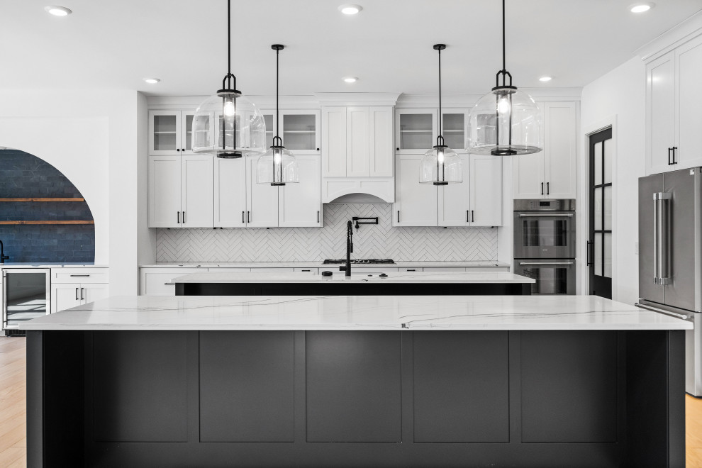 Eat-in kitchen - large transitional eat-in kitchen idea in Cincinnati with a single-bowl sink, shaker cabinets, white cabinets, quartzite countertops, white backsplash, ceramic backsplash, stainless steel appliances, two islands and white countertops
