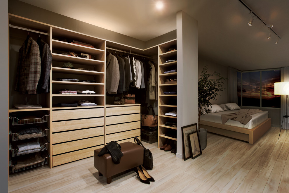 Modern gender-neutral built-in wardrobe in Other with open cabinets, light wood cabinets, light hardwood floors and beige floor.