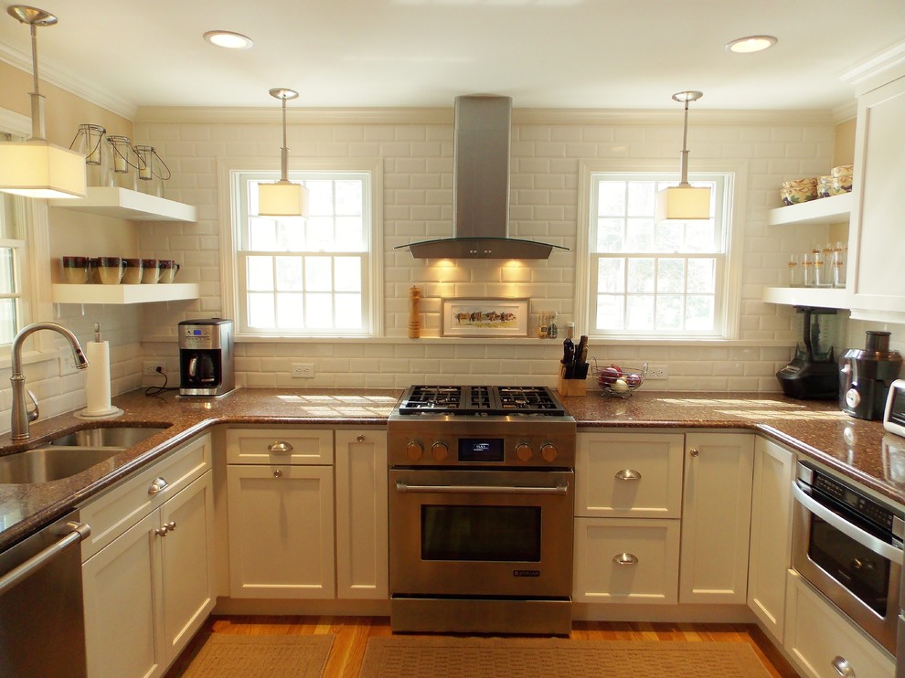 Example of a small transitional u-shaped medium tone wood floor eat-in kitchen design in Boston with an undermount sink, shaker cabinets, white cabinets, solid surface countertops, white backsplash, ceramic backsplash, stainless steel appliances and beige walls