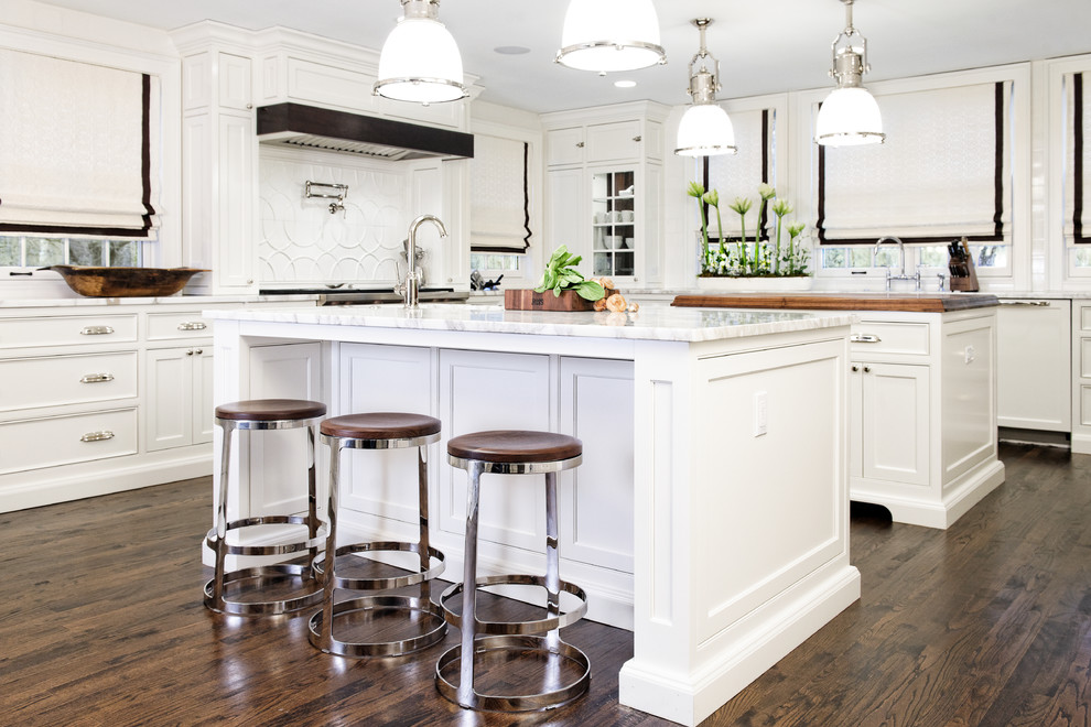 Photo of a large traditional u-shaped eat-in kitchen in Cleveland with an undermount sink, white cabinets, marble benchtops, white splashback, ceramic splashback, panelled appliances, dark hardwood floors and multiple islands.