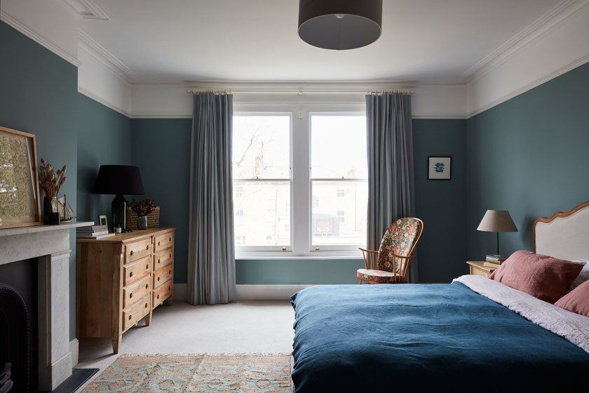 Aménagement d'une grande chambre victorienne avec un mur bleu, un manteau de cheminée en pierre et un sol beige.